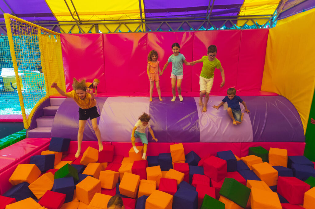 children having fun in trampoline park with foam cubes